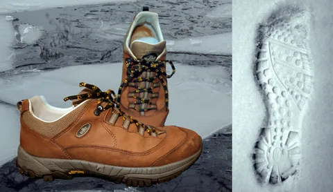 Botas de senderismo junto a una huella en nieve fresca, ambiente invernal en la montaña
