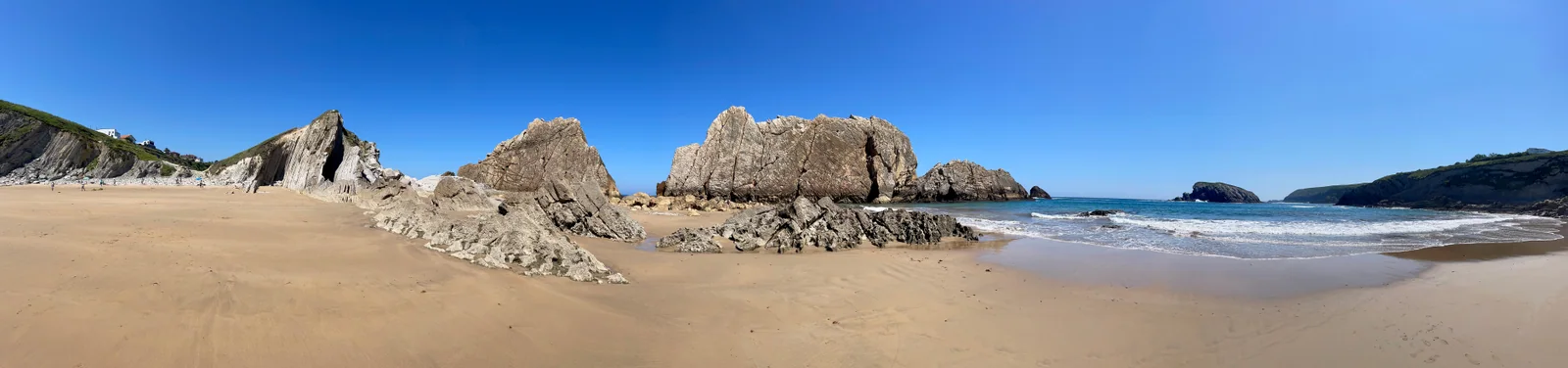 Panorámica de la playa de la Arnía encajada entre acantilados de margas y calizas, con la plataforma de abrasión y los urros al fondo