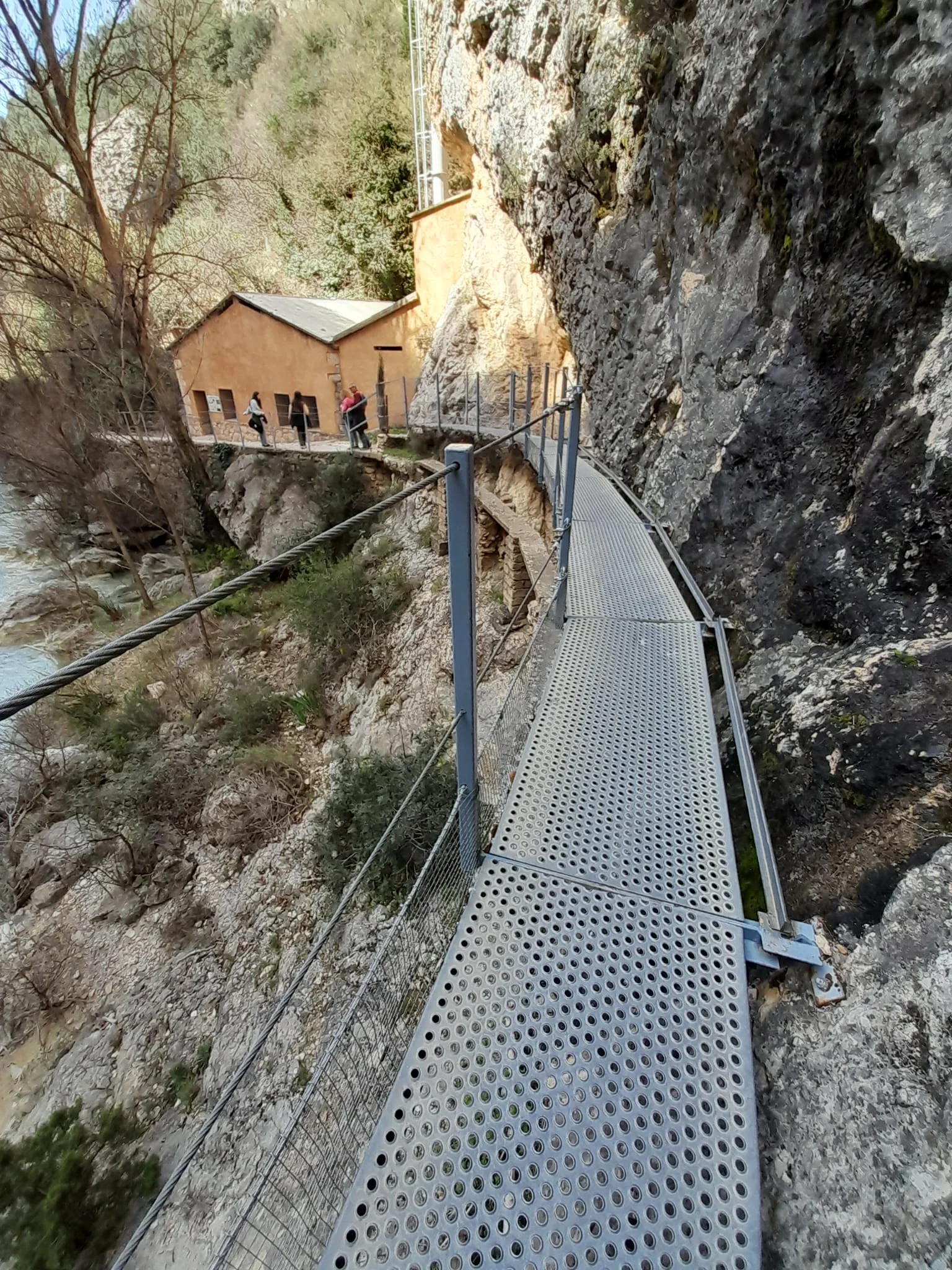 Pasarela junto al río Vero con la antigua central hidroeléctrica de Alquézar al fondo